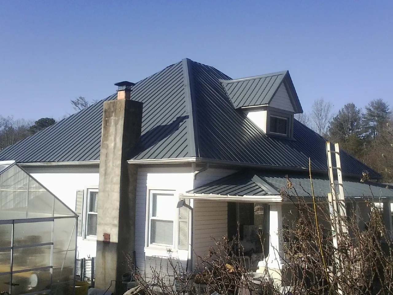 Dark blue standing seam metal roof on a white farmhouse with dormer — Slate & Tile Roof Repair by Roofing Brothers in Cookstown