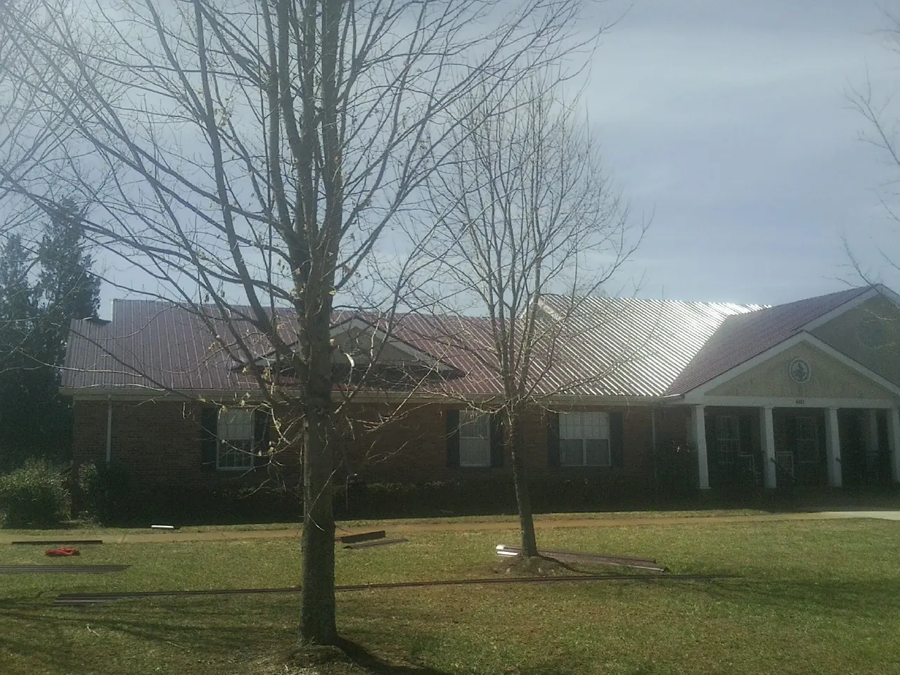 Red metal roof on a brick building seen from the front lawn in Cookstown