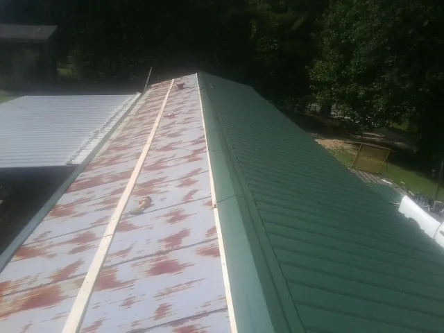 Old rusted panels beside newly installed green metal roofing — Wind Damage Roof Repair by Roofing Brothers in Cookstown