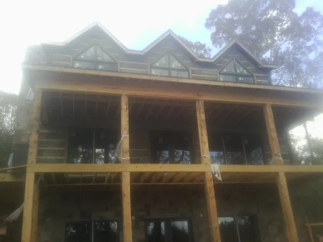 Dormers and porch framing on a large log home under construction — Roof Coating work by our crew in Cookstown