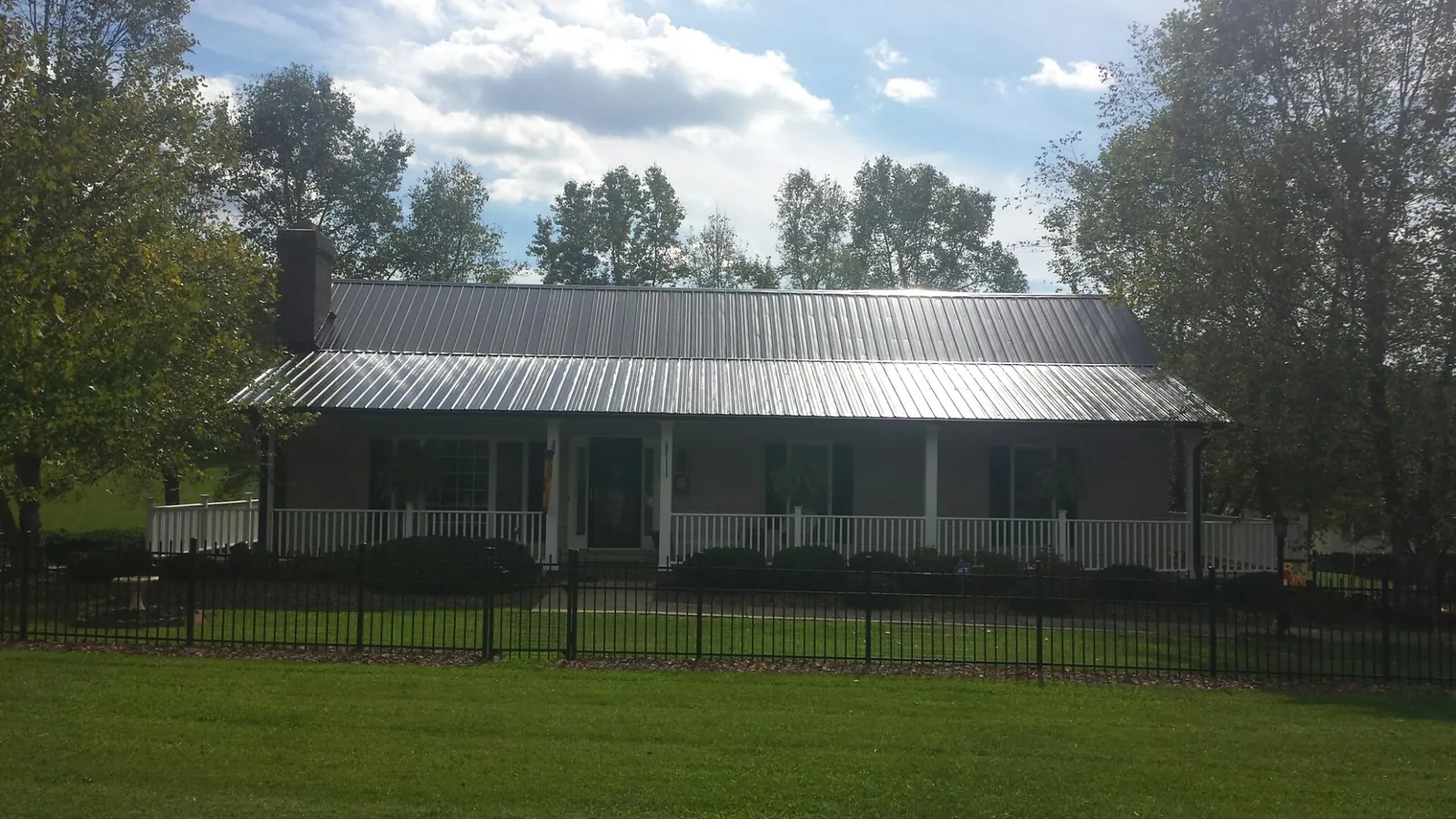 Gray metal roof on a brick ranch with a full width front porch — Gutter Guard Installation work by our crew in Cookstown