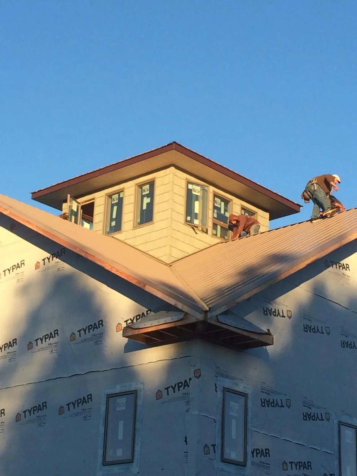 Roofers working around a rooftop cupola on a new metal roof at sunset — Roof Waterproofing in Cookstown by Roofing Brothers